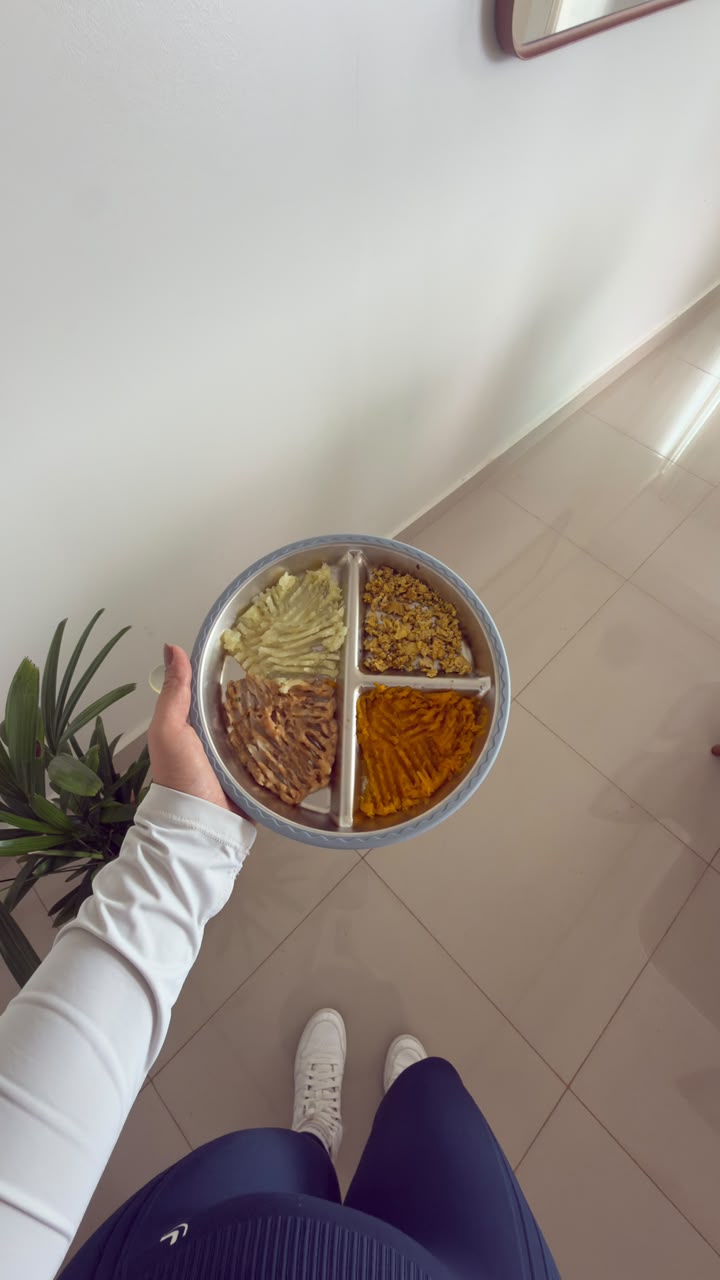Mão segurando pratinho dividido com alimentos variados